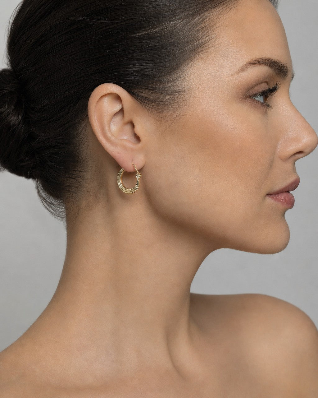 Female model wearing 10K Ribbon Circle Hoop Earrings