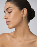 Female model wearing 10K Ribbon Oval Hoop Earrings