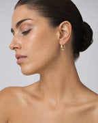 Female model wearing 10K Ribbon Oval Hoop Earrings