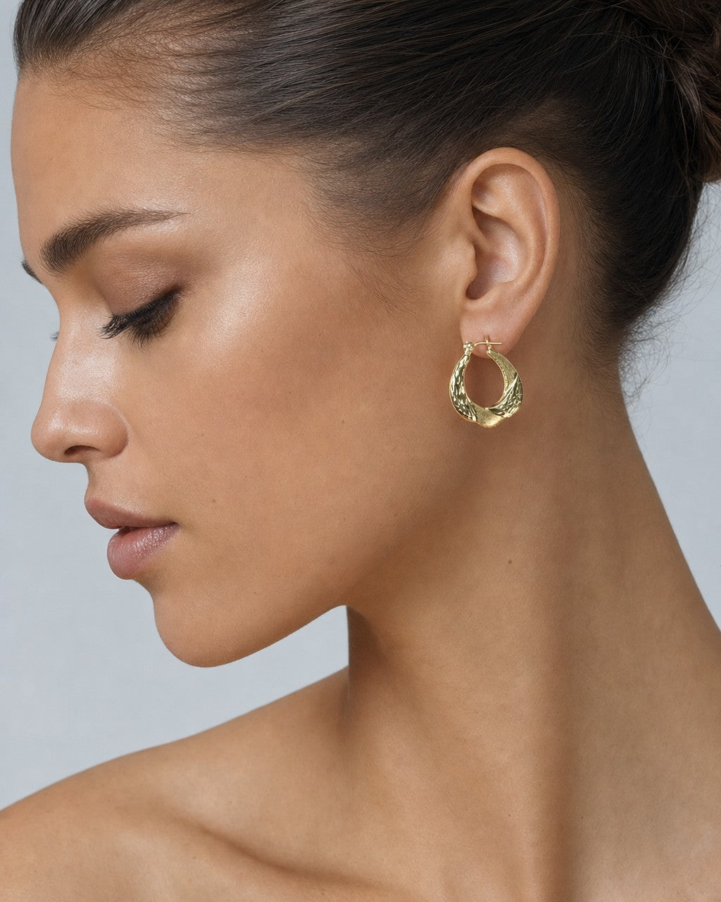 Female model wearing 10K Braided Oval Hoop Earrings