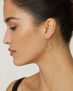Female model wearing 14K Gold Large 2MM Hoop Earrings